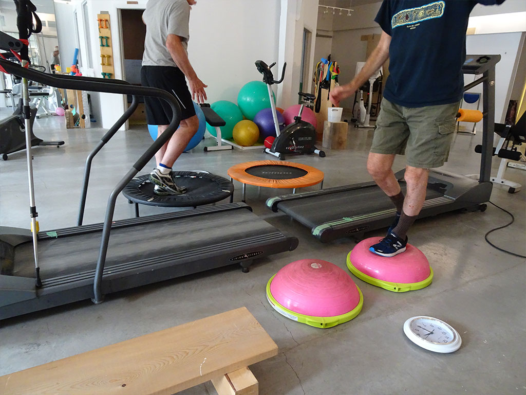 Men practicing balance on balance balls and mini-trampoline at Platypus METT